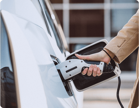 Een afbeelding van een vrouw die haar elektrische auto oplaadt aan het tankstation